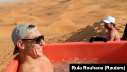 Seorang peserta duduk di bak es selama sesi terapi mandi es di gurun dekat Sharjah, Uni Emirat Arab, 25 Juni 2021. (Foto: REUTERS/Rula Rouhana)