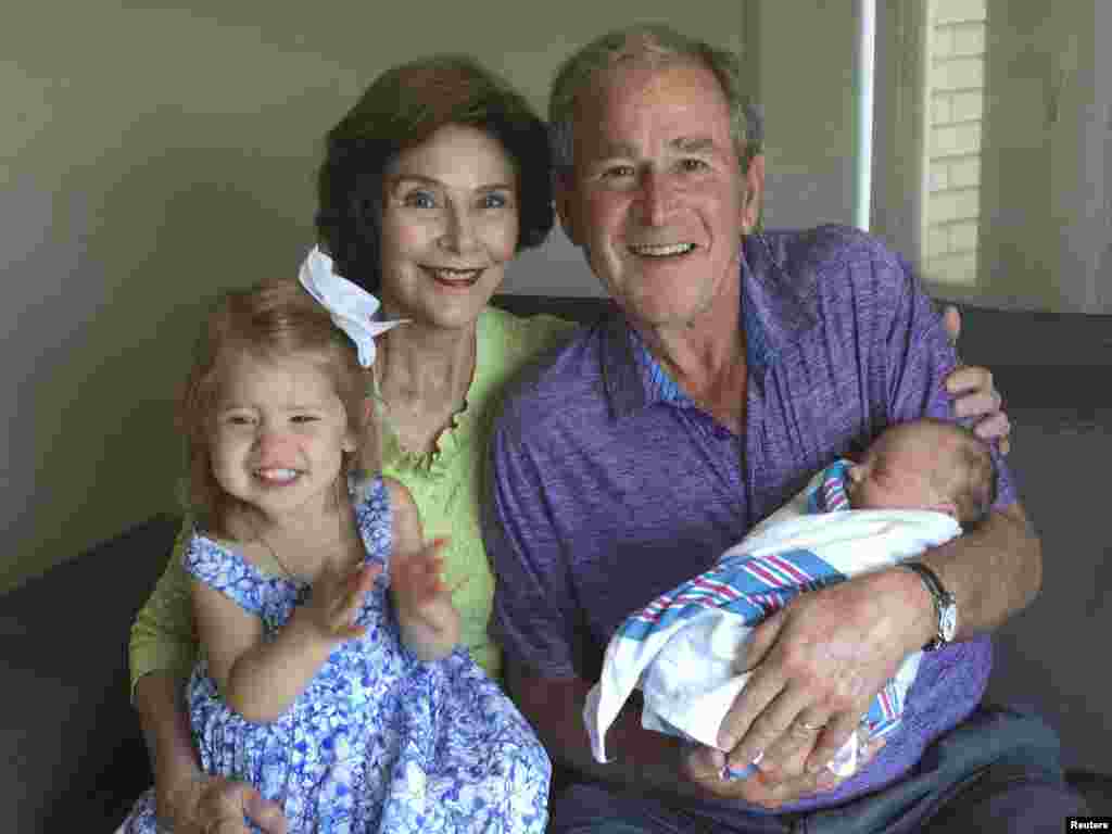 Former U.S. President George W. Bush and his wife Laura pose with their new granddaughter Poppy Louise (R) and her sister Mila Hager, after their daughter Jenna Bush Hager gave birth in New York in a photo provided by the Office of George W. Bush.