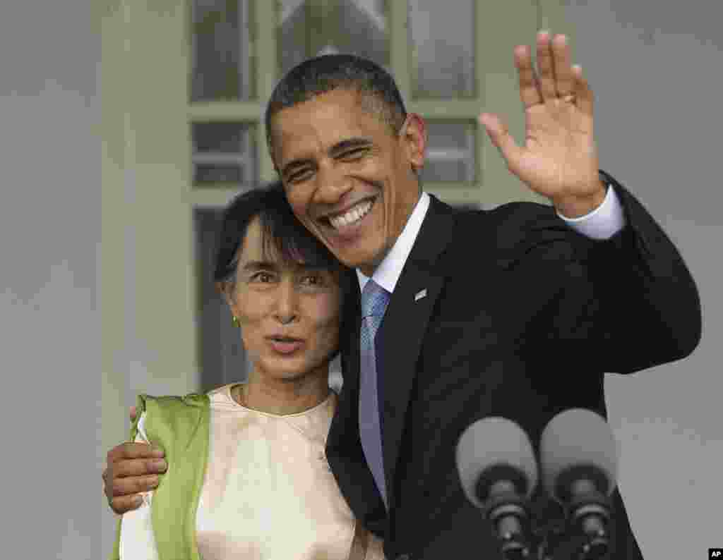 US President Barack Obama, right, waves as he embraces Burmese democracy activist Aung San Suu Kyi after addressing members of the media at her residence in Rangoon, Burma, November 19, 2012. 