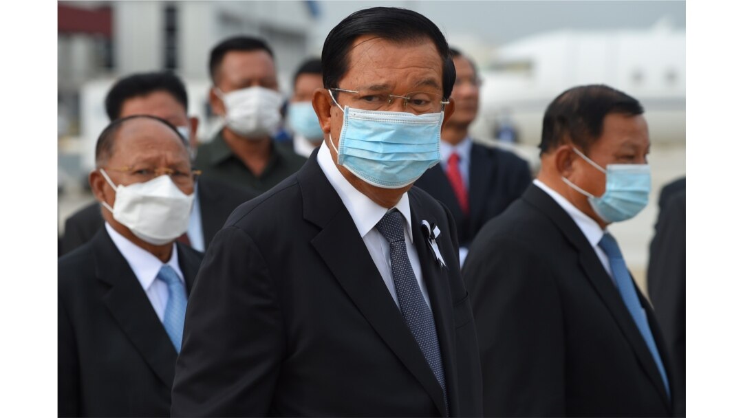 FILE - Prime Minister Hun Sen, center, wears a face mask as a preventive measure against the spread of the COVID-19 novel coronavirus, at Phnom Penh International Airport, May 11, 2020.