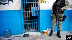Un officier de police est à l'extérieur d'une cellule où a eu lieu la mutinerie, à Arcahaiea, Haïti, le 22 octobre 2016.