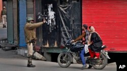 Seorang tentara paramiliter menghentikan sepeda motor yang dikendarai oleh warga sipil di wilayah Srinagar, wilayah Kashmir yang dikontrol India (5/11). Toko-toko dan bisnis tutup di Kashmir Utara sebagai bagian dari aksi protes warga menyusul tewasnya dua remaja oleh tentara bersejata di jalanan kota tersebut dua hari yang lalu.