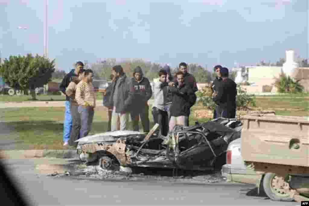 This photograph, obtained by The Associated Press outside Libya and taken by an individual not employed by AP, shows men standing next to a damaged vehicle during recent days' unrest in Benghazi, Libya. (AP Photo) EDITOR'S NOTE: THE AP HAS NO WAY OF INDEP