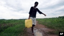 Woman carries water collected from a broken main water supply pipe in Kambuzuma, Harare (2009 photo)