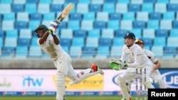 Pakistan's Asad Shafiq bats as England's Jos Buttler looks on during a Pakistan-England match at Dubai International Stadium, United Arab Emirates on Oct. 22, 2105.