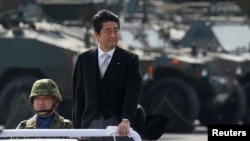 FILE - Japanese Prime Minister Shinzo Abe reviews Japanese Self-Defense Forces' (SDF) troops during the annual SDF ceremony at Asaka Base, Japan, Oct. 23, 2016.