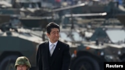 In this file photo, Japanese Prime Minister Shinzo Abe reviews Japanese Self-Defense Forces' (SDF) troops during the annual SDF ceremony at Asaka Base, Japan, Oct. 23, 2016.