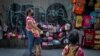 A child hugs her mother as a sibling watches at their sidewalk shop aimed for tourists in Bangkok, Thailand, July 29, 2020. 