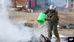 FILE - A riot police officer puts out a fire during a mass rally called by the opposition leader Raila Odinga over the high cost of living, in Nairobi, Monday, March 27, 2023.