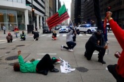 A protester lies on the ground as others follow to take a knee during a peaceful protest on April 14, 2021, along South Michigan Avenue in Chicago ahead of the video release of fatal police shooting of 13-year-old Adam Toledo.