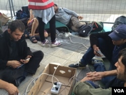 Smartphones help migrants determine routes and sustain vital connections. Aid workers have set up charging stations for them in Vienna, Austria. (H. Murdock/VOA).