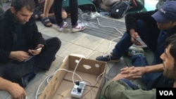 Migrants rechargeant leurs téléphones portables à Vienne, en Autriche. (Heather Murdock / VOA).