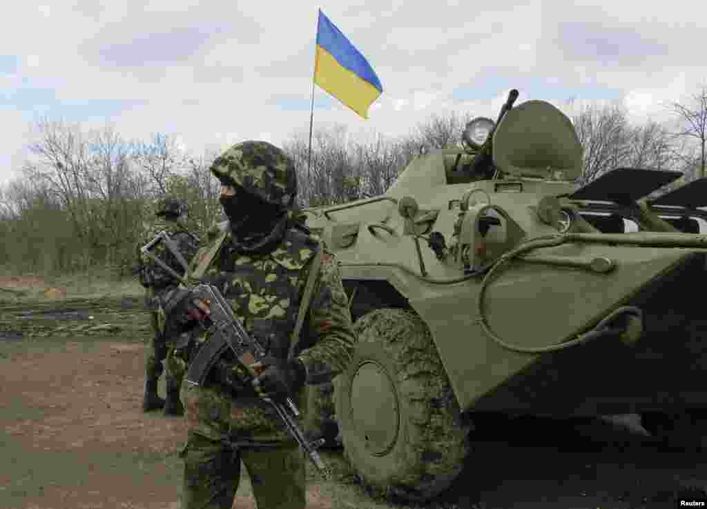 Ukrainian soldiers are seen near armored personnel carriers at a checkpoint near the town of Izium in Eastern Ukraine, April 15, 2014. 