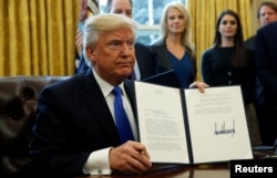 U.S. President Donald Trump holds up a signed executive order to advance construction of the Keystone XL pipeline at the White House in Washington, Jan. 24, 2017.