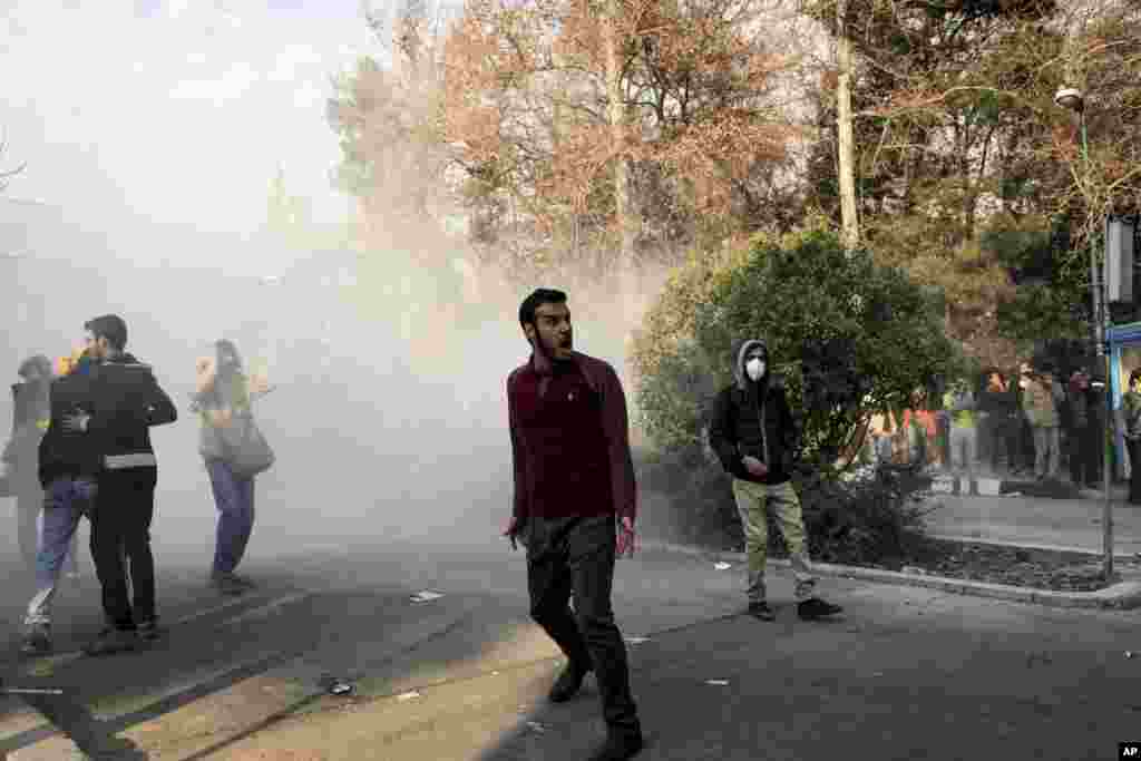 In this photo taken by an individual not employed by the Associated Press and obtained by the AP outside Iran, university students attend a protest inside Tehran University while a smoke grenade is thrown by anti-riot Iranian police, in Tehran, Dec. 30, 2017.