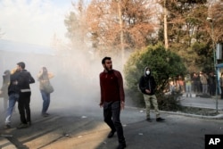 In this photo taken by an individual not employed by AP and obtained by the AP outside Iran, university students attend a protest inside Tehran University while a smoke grenade is thrown by anti-riot Iranian police, in Tehran, Dec. 30, 2017.