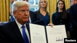 U.S. President Donald Trump holds up a signed executive order to advance construction of the Keystone XL pipeline at the White House in Washington January 24, 2017. REUTERS/Kevin Lamarque