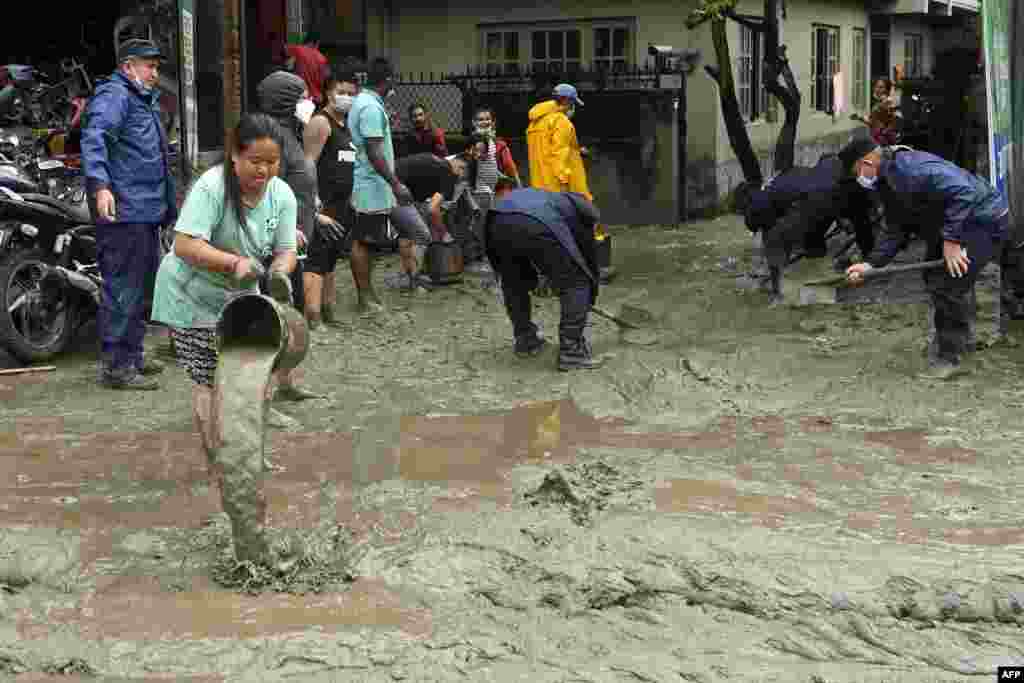 Residents and rescue workers clean an area which was flooded after Bishnumati river overflowed following heavy monsoon rains in Kathmandu, Nepal.