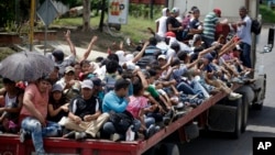 Honduran migrants who are traveling to the United States as a group, get a free ride in the back of a trailer truck flatbed, as they make their way through Teculutan, Guatemala, Oct. 17, 2018.