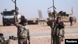  FILE - Syrian Democratic Forces (SDF) fighters hold up their weapons in the north of Raqqa city, Syria.