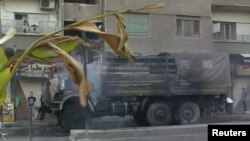 Khói bốc lên từ một chiếc xe tải quân sự của lực lượng chính phủ Syria bị đốt cháy tại Damascus, ngày 18/7/2012