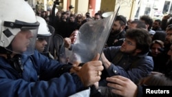 FILE - Demonstrators scuffle with riot police officers during a protest against home auctions in Thessaloniki, Greece, Nov. 29, 2017.