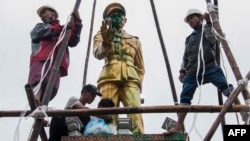 FILE - workers clean a vandalized statue of Myanmar independence hero Gen. Aung San, in Myitkyina, capital of Kachin state, Myanmar, July 23, 2018.