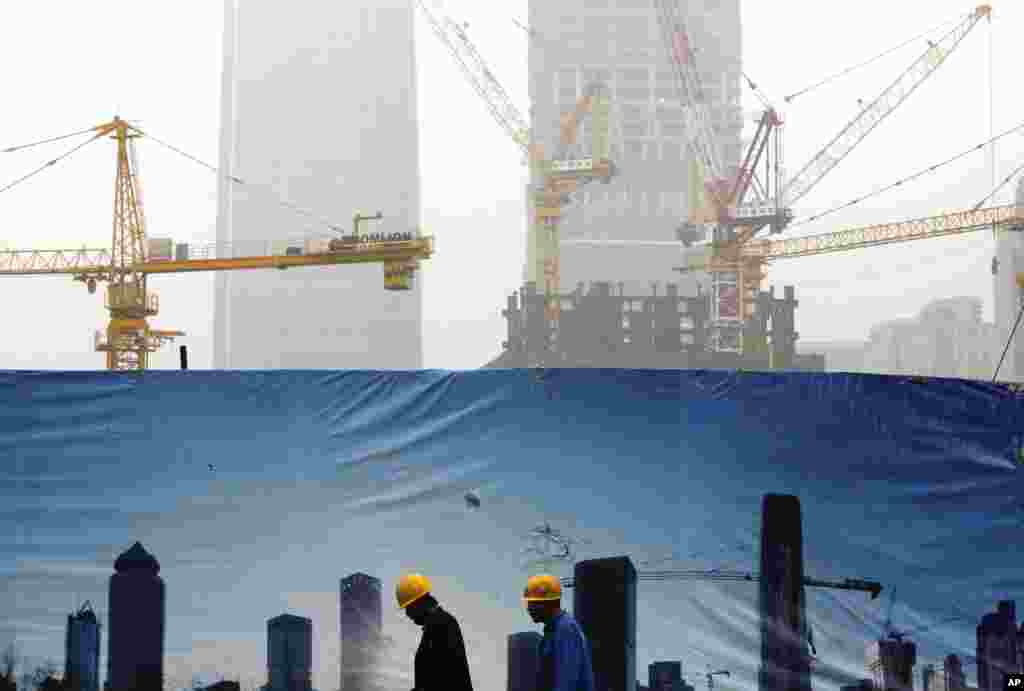 중국 베이징의 한 건설현장 뒤편으로 고층건물들이 스모그에 덮여있다. 공사장 외벽에 걸린 청명한 하늘 사진과 대조적이다.