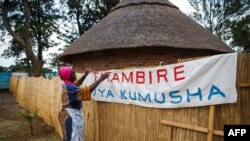 Hatifari Munongi, poète, conteuse et institutrice à la retraite, ajuste une banderole de bienvenue dans la réplique d’une habitation traditionnelle qu'elle a installé dans l'arrière-cour de sa maison dans la banlieue de Marlborough à Harare le 18 octobre 2018