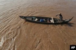 FILE - A Cambodian Muslim man rows his wooden boat where he lives along the Mekong River bank at a fisherman floating village located in Kball Chroy, near Phnom Penh, Cambodia, on Monday, Sept. 9, 2019. (AP Photo/Heng Sinith)