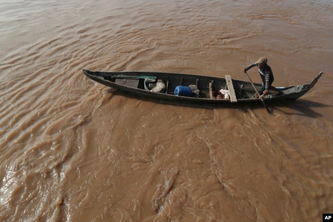 FILE - A Cambodian Muslim man rows his wooden boat where he lives along the Mekong River bank at a fisherman floating village located in Kball Chroy, near Phnom Penh, Cambodia, on Monday, Sept. 9, 2019. (AP Photo/Heng Sinith)