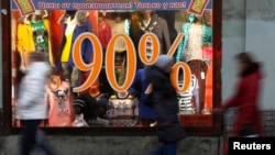Orang-orang berjalan melewati iklan potongan harga di toko di St. Petersburg, Rusia, 7 November 2014. (Foto: dok.)