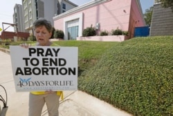FILE - In this Oct. 2, 2019. file photo, an abortion opponent sings to herself outside the Jackson Womens Health Organization clinic in Jackson, Miss. (AP Photo/Rogelio V. Solis, File)