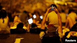 A protester takes pictures of fellow demonstrators as they block the main street to Hong Kong's financial Central district, September 29, 2014.