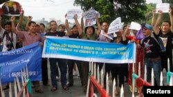 Protesters chant slogans while they stand behind police barricade by the Hoan Kiem lake during an anti-China protest in Hanoi, Jun. 2, 2013. 