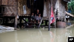 A woman and her child look out from their residence half-submerged in floodwaters in Bago, 80 kilometers northeast of Yangon, Myanmar, Saturday, Aug 1, 2015.