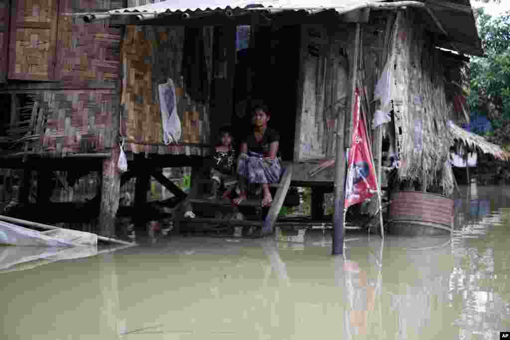A woman and her child look out from their hut half-submerged in floodwaters in Bago, 80 kilometers northeast of Yangon, Myanmar, Aug. 1, 2015.