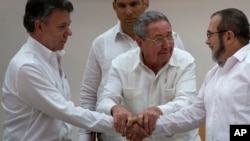 FILE - Cuba's President Raul Castro (C) encourages Colombian President Juan Manuel Santos (L) and Commander the Revolutionary Armed Forces of Colombia or FARC, Timoleon Jimenez, to shake hands, in Havana, Cuba, Sept. 23, 2015.