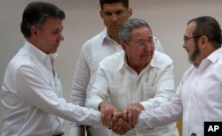 FILE - Cuba's President Raul Castro (C) encourages Colombian President Juan Manuel Santos (L) and Commander the Revolutionary Armed Forces of Colombia or FARC, Timoleon Jimenez, to shake hands, in Havana, Cuba, Sept. 23, 2015.