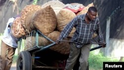 FILE - Young men carting sacks of potatoes to the market encounter a steep hill just outside Nairobi, Kenya, June 13, 2001. 
