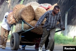 FILE - Young men carting sacks of potatoes to the market encounter a steep hill just outside Nairobi, Kenya, June 13, 2001.