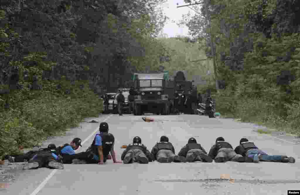 Thai policemen and soldiers take up position during a search for explosives in the village of Raman after local farmers alerted them to suspicious activities in Yala province, south of Bangkok, Thailand.