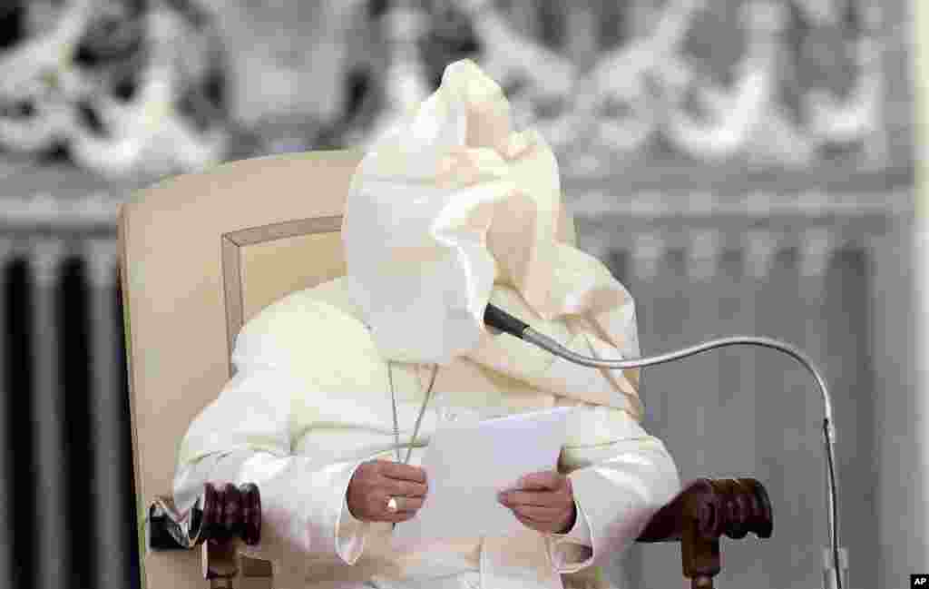 A gust of wind blows Pope Francis' mantle as he reads his weekly message in St. Peter's Square at the Vatican. 