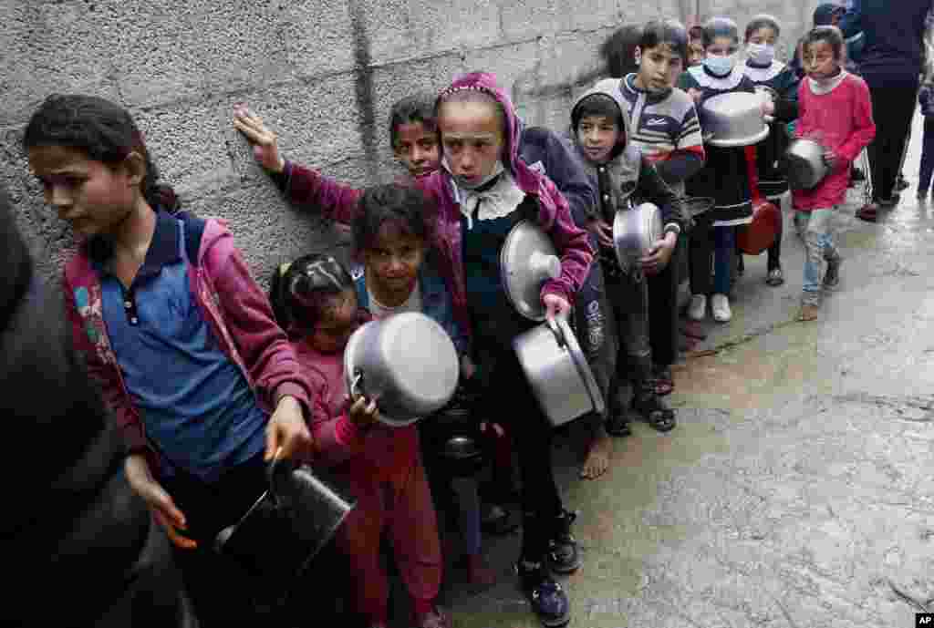 Palestinian children wait in line to receive free meals in Gaza City.