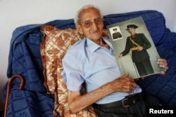 Gumersindo Cubo, 101, poses for a portrait with a picture of himself when he was young, in his home in Casavieja, Avila, near Madrid, Spain, July 12, 2016.