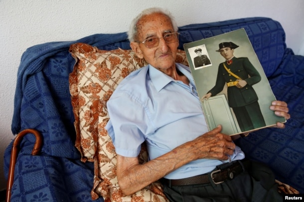 Gumersindo Cubo, 101, poses for a portrait with a picture of himself when he was young, in his home in Casavieja, Avila, near Madrid, Spain, July 12, 2016.