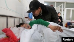 An elderly man talks to a girl who was injured after a stampede accident at a primary school, at a hospital in Xiangyang, Hubei province, China, Feb. 27, 2013.