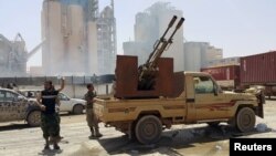 FILE - Members of forces loyal to Libya's eastern government stand near to the Libyan cement factory after the army took control of the factory following clashes with the Shura Council of Libyan Revolutionaries, an alliance of former anti-Gaddafi rebels who have joined forces with Islamist group Ansar al-Sharia, in Benghazi, Libya.