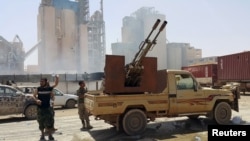 FILE - Members of forces loyal to Libya's eastern government stand near to the Libyan cement factory after the army took control of the factory following clashes with the Les membres des forces loyales au gouvernement de l'Est de la Libye aperçus près de l'usine de ciment libyen dont l'armée a pris le contrôle après des affrontements avec le Conseil de la Choura des révolutionnaires libyens, une alliance d’anciens rebelles anti-Kadhafi qui ont uni leurs forces avec le groupe islamiste Ansar al -Sharia, à Benghazi, en Libye 18 Avril 2016. REUTERS / Stringer - RTX2AHYZShura Council of Libyan Revolutionaries, an alliance of former anti-Gaddafi rebels w