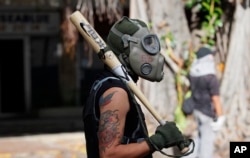 A protester uses a baseball bat and gas mask during clashes with security forces blocking an opposition march from reaching the National Electoral Council headquarters in Caracas, Venezuela, May 24, 2017.